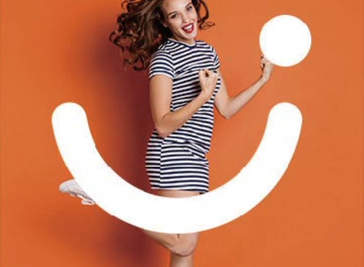 A woman laughing at the camera beside a giant white smile