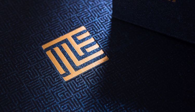 ML gold cipher on navy with a geometric maze pattern