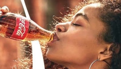 Woman drinking from a Coke bottle with her eyes closed