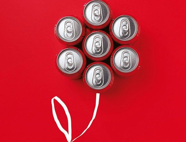 Coke cans arranged as a balloon bouquet, flat lay on red