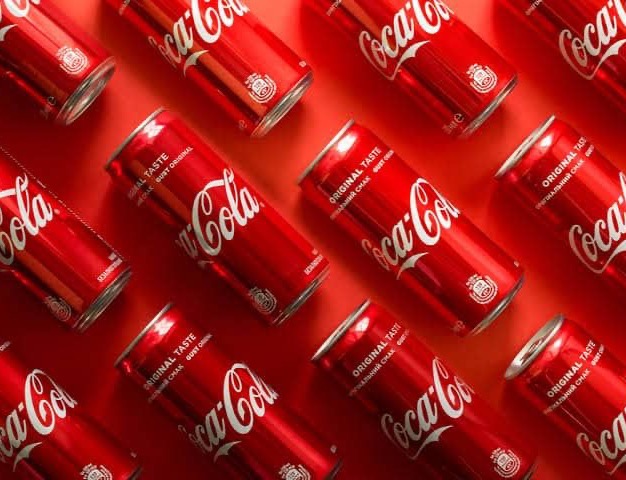 Diagonal flat-lay grid of Coke cans, red on red