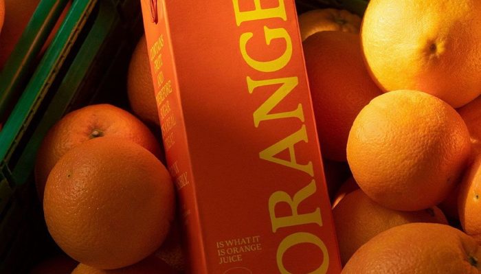 A monochrome pack shot sunk into a bed of real oranges