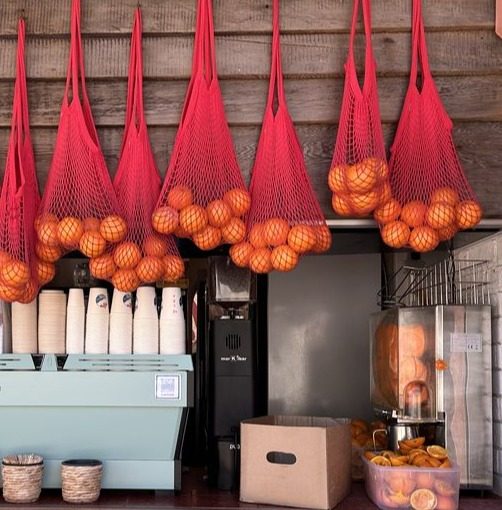 String bags of fruit hanging over a juice counter